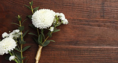 Small stylish boutonnieres on wooden table, top view. Space for text