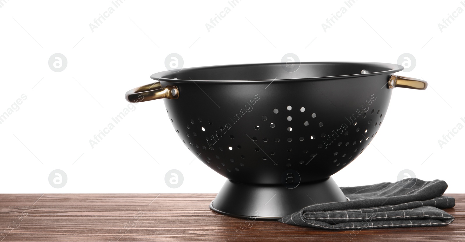 Photo of Black empty colander and napkin on wooden table against white background. Space for text