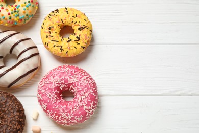 Yummy donuts and space for text on white wooden background, flat lay