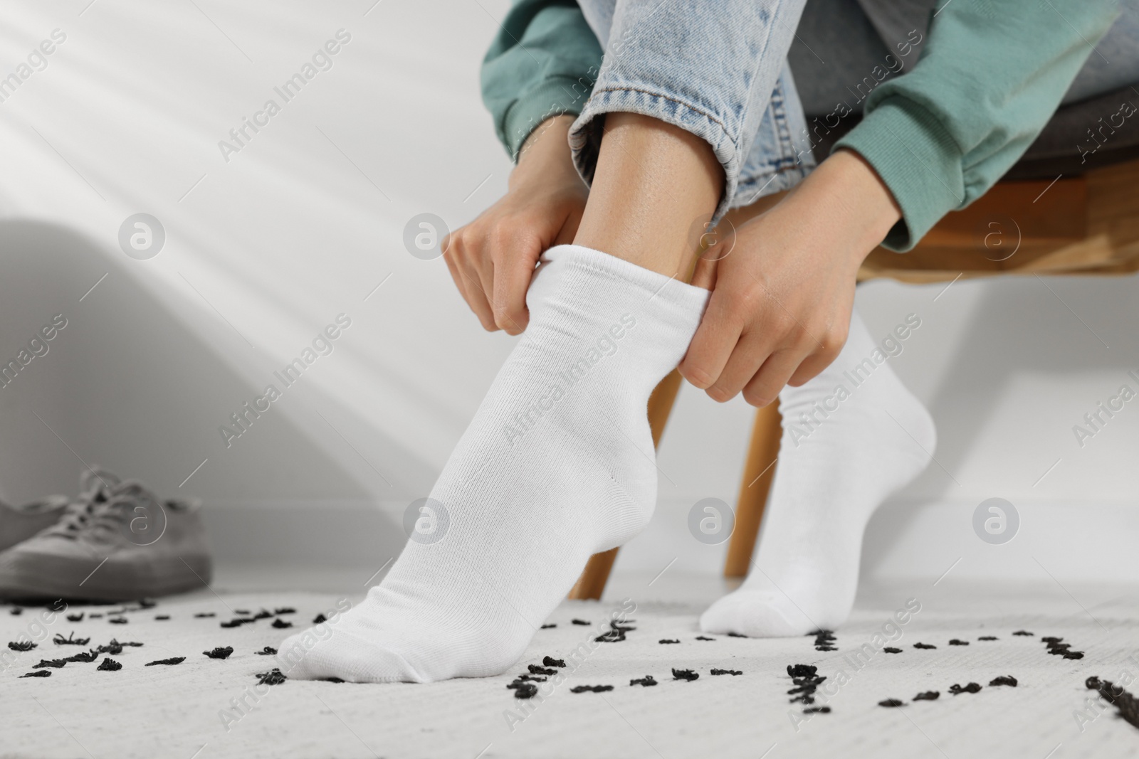 Photo of Woman putting on white socks at home, closeup