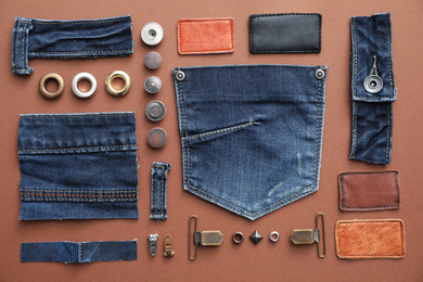 Photo of Flat lay composition with garment accessories and cutting details for jeans on brown background
