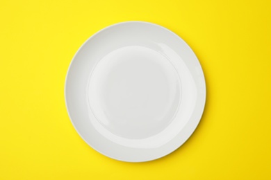 Clean empty plate on color background, top view