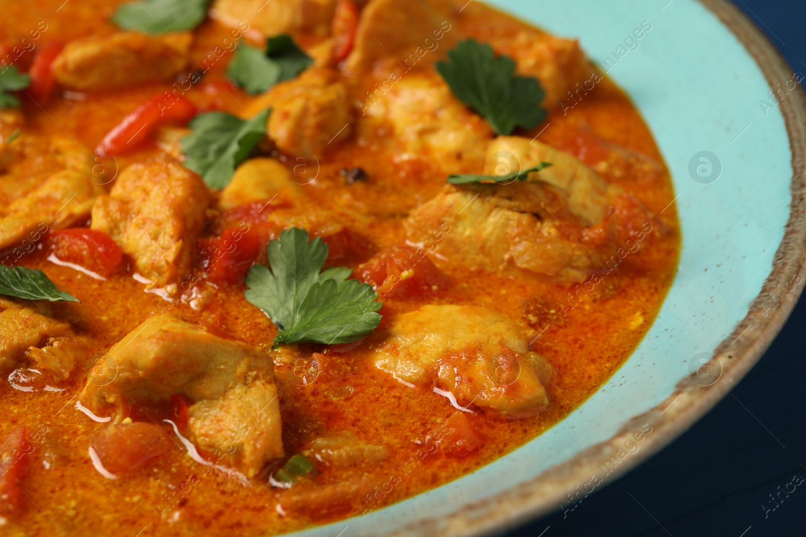 Photo of Delicious chicken curry with parsley on table, closeup