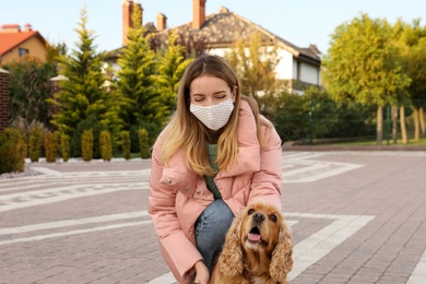 Woman in protective mask with English Cocker Spaniel outdoors. Walking dog during COVID-19 pandemic