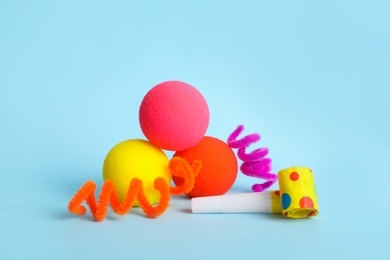 Photo of Clown noses, party blower and fluffy wires on light blue background