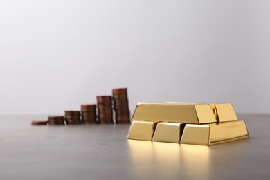 Photo of Stacked gold bars and coins on table. Space for text