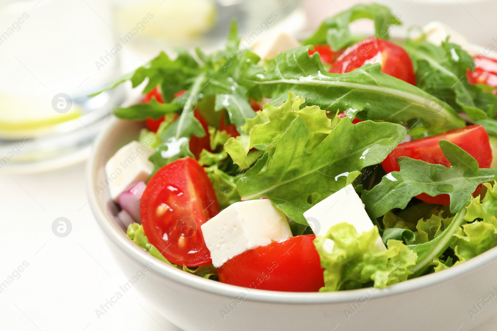 Photo of Delicious salad with arugula and vegetables on white table, closeup