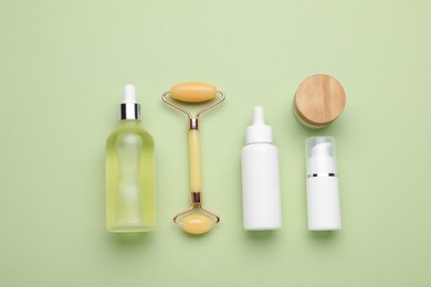 Photo of Natural face roller and cosmetic products on light green background, flat lay