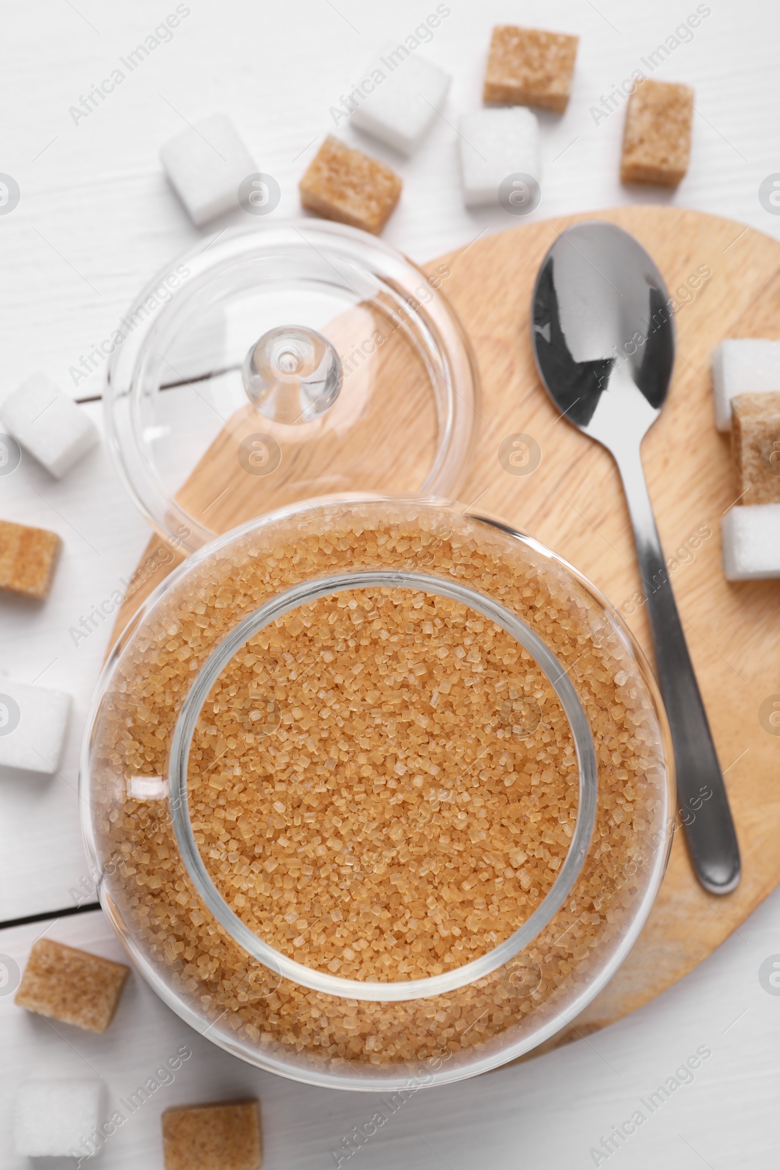 Photo of Brown sugar in jar and spoon on white wooden table, top view