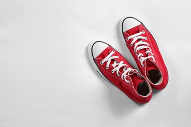 Pair of new stylish red sneakers on white fabric, flat lay. Space for text