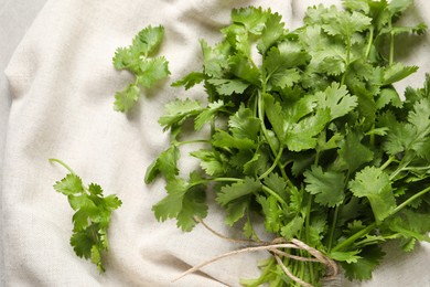 Photo of Fresh green cilantro with twine on white fabric, flat lay