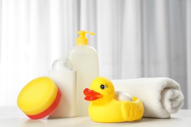 Photo of Baby cosmetic products, toy and towel on table indoors