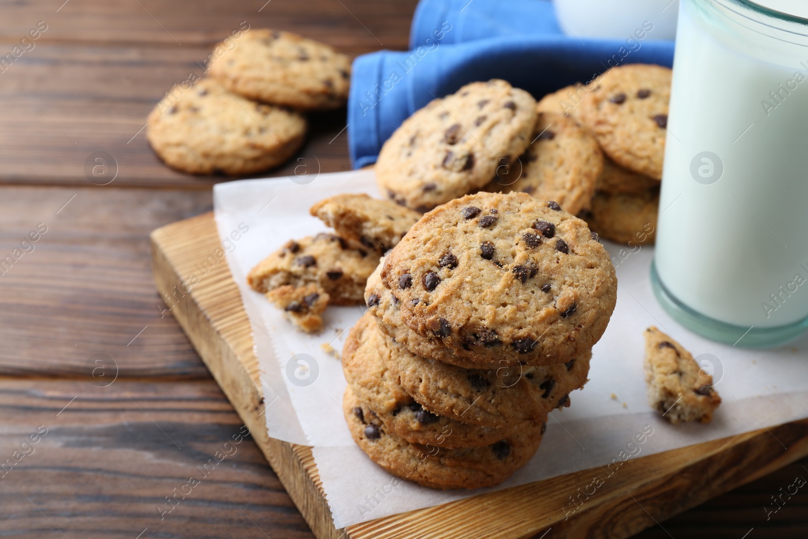 Photo of Delicious chocolate chip cookies and glass of milk on wooden table, space for text