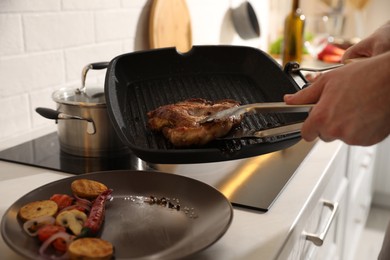Photo of Man taking cooked tasty meat from frying pan, closeup
