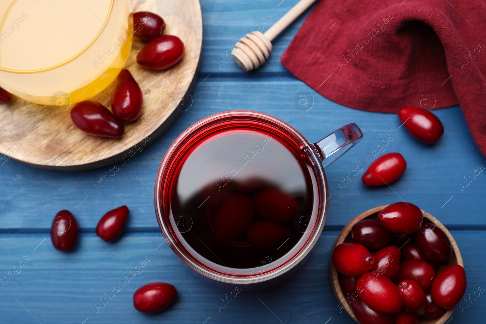 Photo of Flat lay composition with fresh dogwood tea and berries on blue wooden table