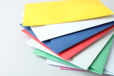 Photo of Colorful paper envelopes on light background, closeup