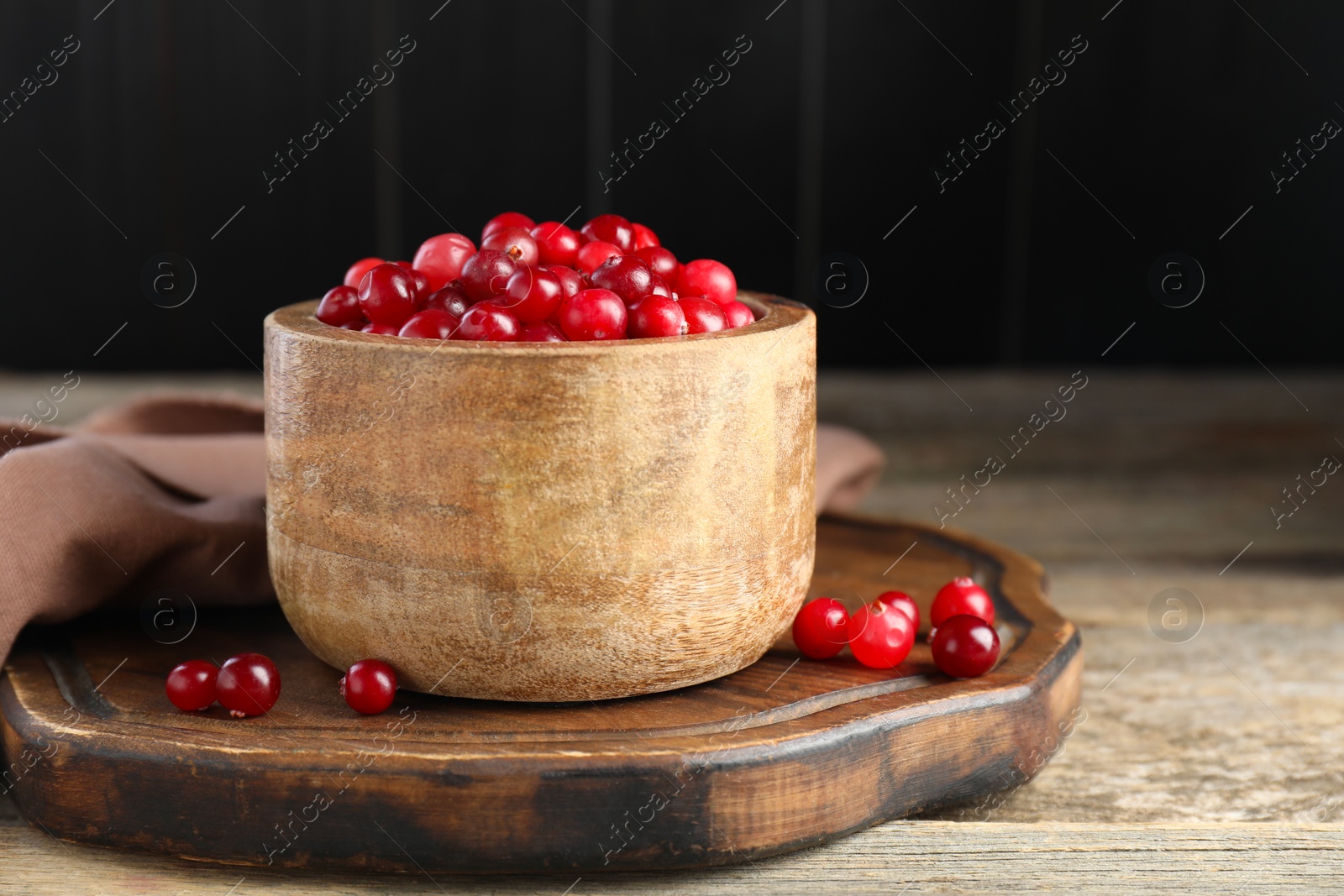 Photo of Ripe cranberries in bowl on wooden table