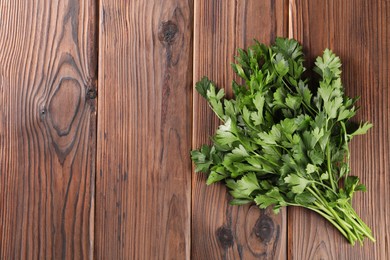 Photo of Bunch of fresh green parsley leaves on wooden table, top view. Space for text
