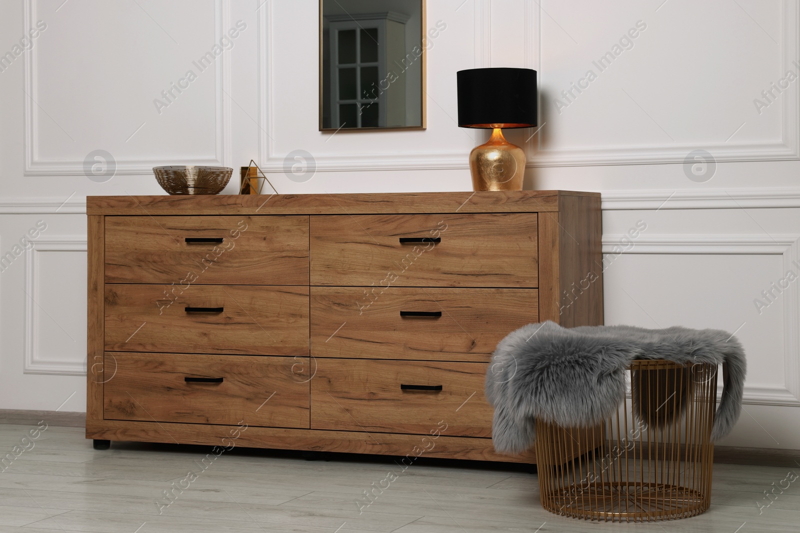 Photo of Stylish room interior with chest of drawers, mirror and decor elements