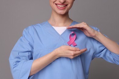 Photo of Mammologist with pink ribbon on gray background, closeup. Breast cancer awareness