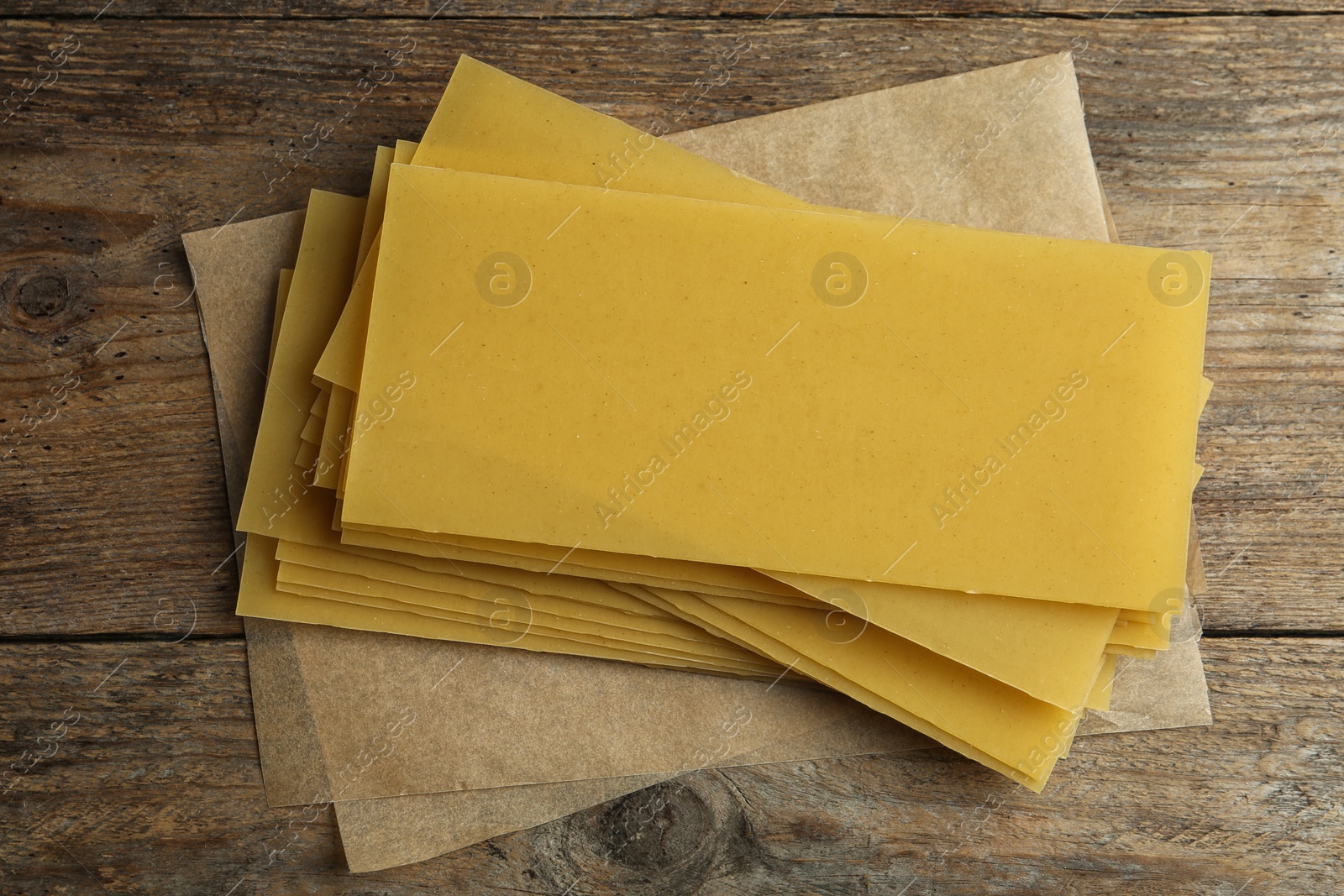 Photo of Uncooked lasagna sheets on wooden background, top view