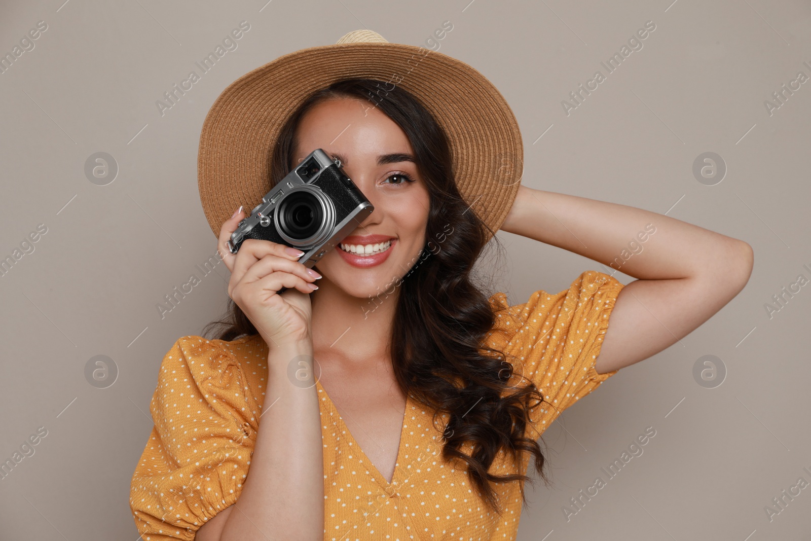 Photo of Beautiful young woman with straw hat and camera on beige background