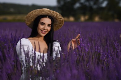 Beautiful young woman with straw hat in lavender field