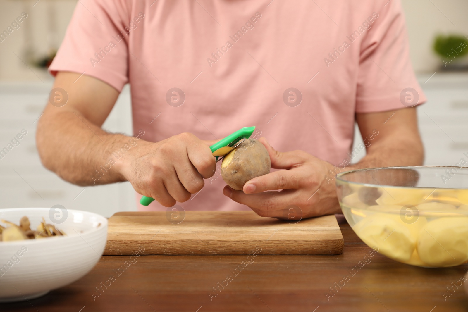 Photo of Man peeling potato at table, closeup. Preparing vegetable