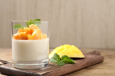 Photo of Delicious panna cotta with mango on wooden table. Space for text