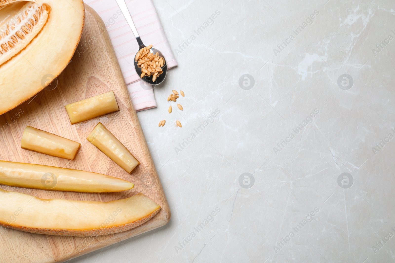 Photo of Sliced delicious ripe melon on grey marble table, flat lay. Space for text