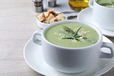 Photo of Delicious asparagus soup with green onion served on white wooden table