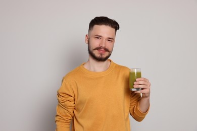 Photo of Handsome young man with glass of juice on light grey background