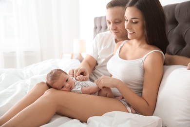 Photo of Happy couple with their newborn baby on bed