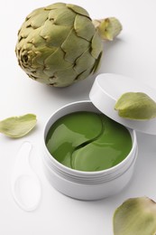 Package of under eye patches and artichoke on white background. Cosmetic product