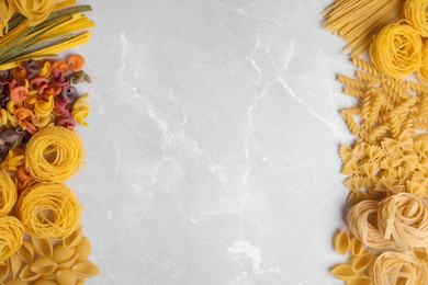 Photo of Different types of pasta on light grey marble table, flat lay. Space for text