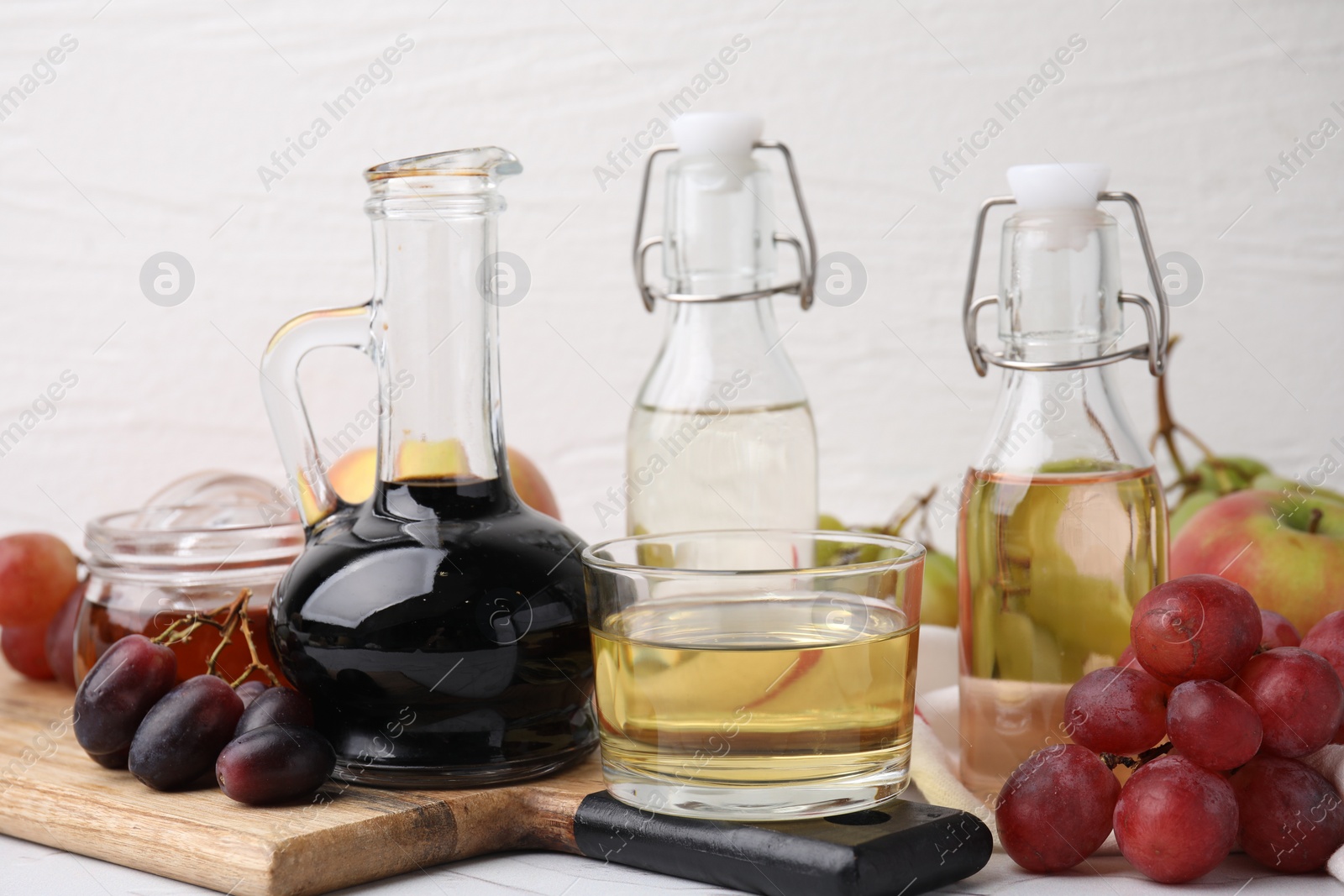 Photo of Different types of vinegar and fresh fruits on table