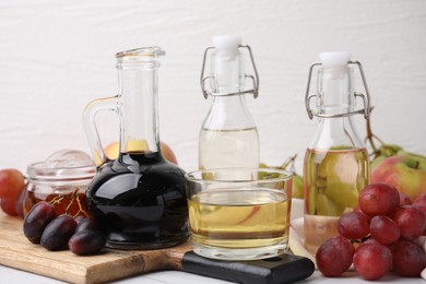 Photo of Different types of vinegar and fresh fruits on table