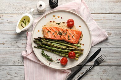 Photo of Tasty grilled salmon with tomatoes, asparagus and spices served on wooden table, flat lay