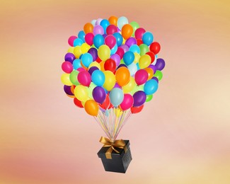 Image of Many balloons tied to gift box on coral background