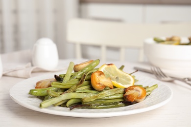 Delicious baked green beans with lemon and mushrooms on white table, closeup