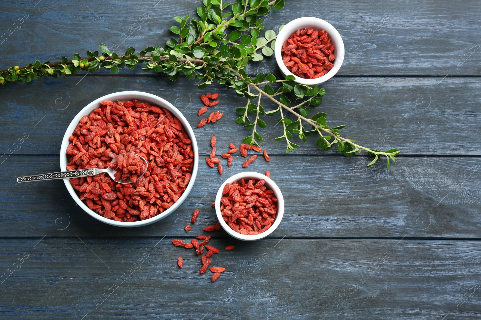 Photo of Flat lay composition with dried goji berries on blue wooden table. Healthy superfood