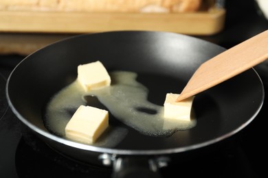 Photo of Stirring melting butter in frying pan on table, closeup