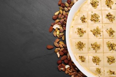 Making delicious baklava. Raw dough with different nuts on black textured table, flat lay. Space for text