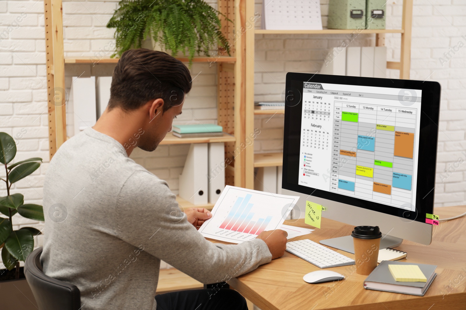 Photo of Handsome man using calendar app on computer in office