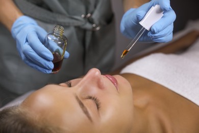 Photo of Cosmetologist applying serum on client's face in salon