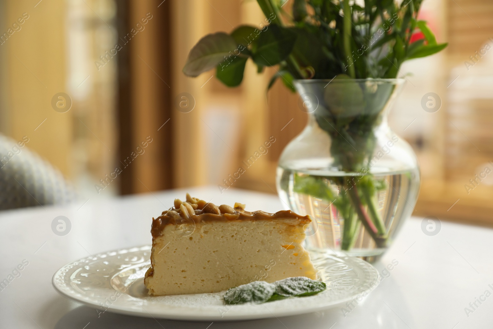 Photo of Tasty dessert and vase with flowers on white table indoors