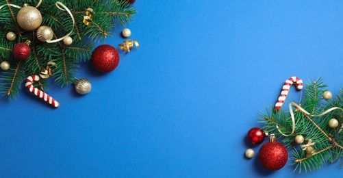 Photo of Fir tree branches with Christmas decoration on blue background, flat lay. Space for text