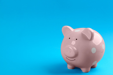 Photo of Pink piggy bank on blue background. Space for text