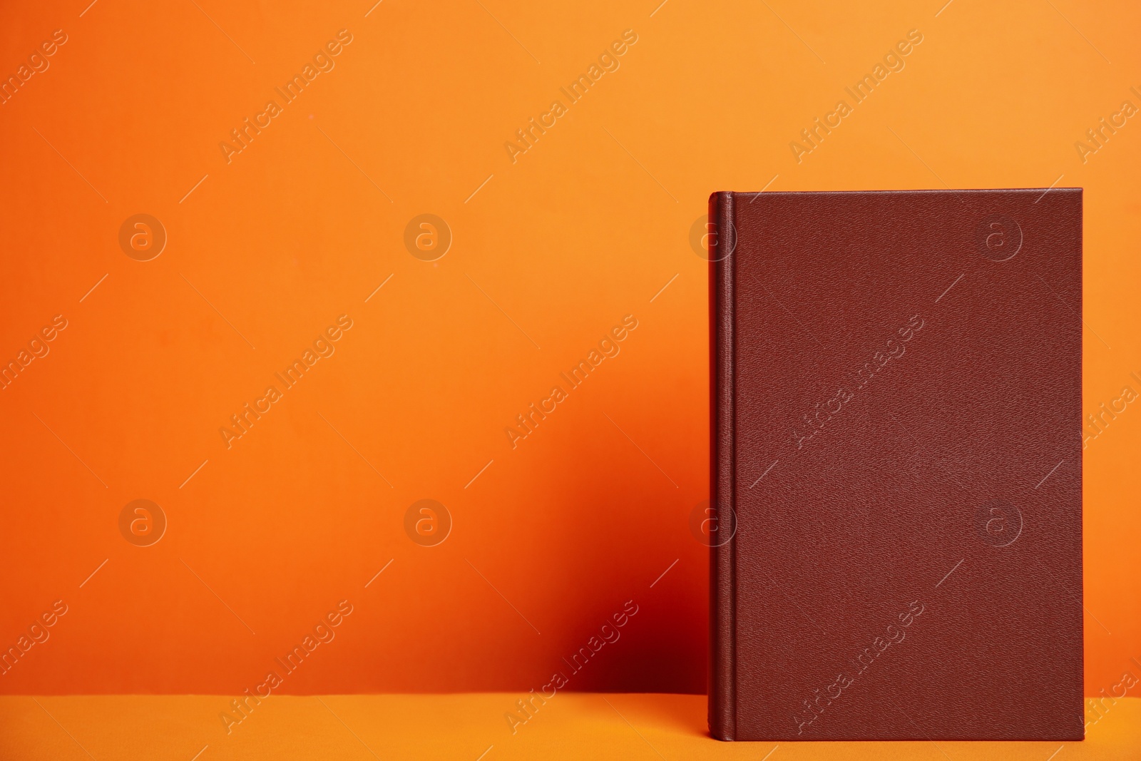 Photo of Hardcover book on orange background. Space for design