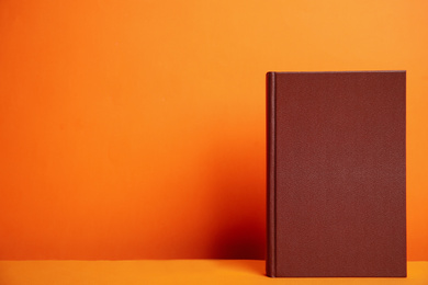 Hardcover book on orange background. Space for design